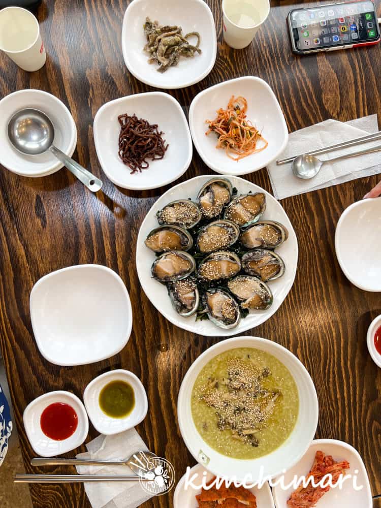 table setting of side dishes and abalone sashimi and porridge