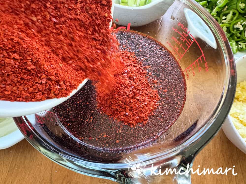 adding gochugaru to perilla kimchi seasoning