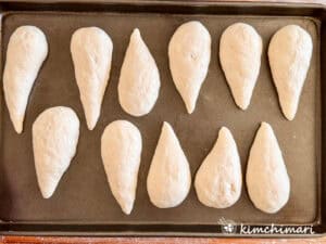 cone shaped salt bread rolls on dark pan